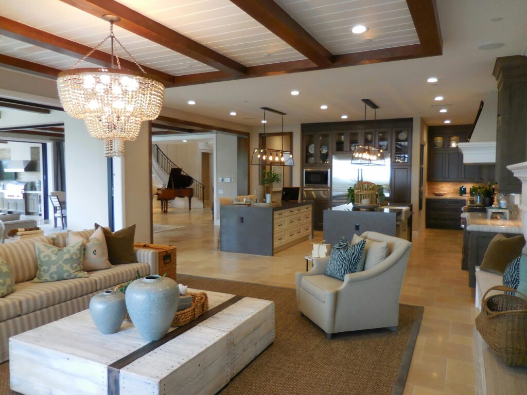 pexels-photo-3701434-3701434 Spacious living room with elegant decor and an open kitchen area, featuring a chandelier and comfortable furnishings.